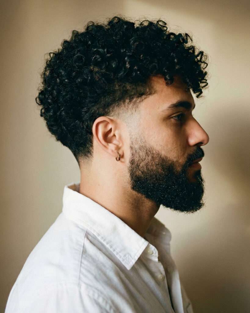 homem com corte  de cabelo masculino taper fade com cachos no topo